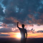 Motivated person silhouette raising fist at sunset, symbolizing self-discipline, personal growth, success, and motivation for professional development.
