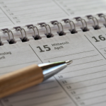 Close-up of a planner with scheduled dates and a pen, representing time management, planning, and professional organization.